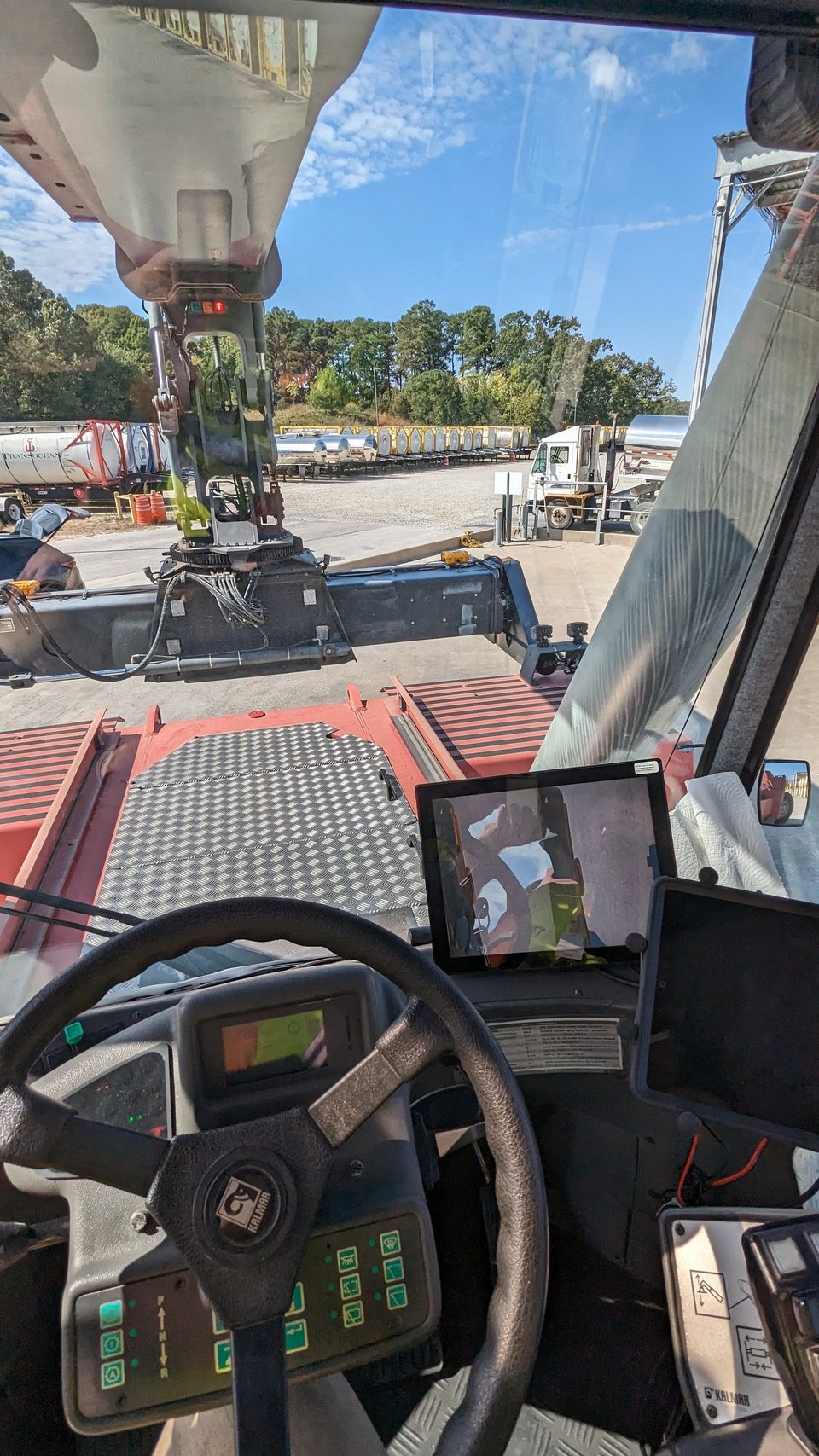 Reach stacker cab with a HoistCam monitor beside the steering wheel showing the view from the spreader